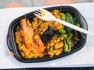 Classic paella with shrimp rice and pepper in black plastic plate