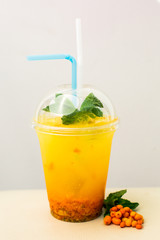 Sea-buckthorn drink in a plastic cup with straws