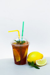 Ice tea with lemon and mint in a plastic cup with straws