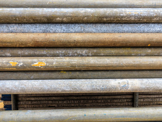 Mental scaffold pipe stack together on scaffold plank wood shelve with blue, green and yellow mark at the tip for build the temporary structure.