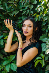 Portrait of young sexy brunette with black grapes.