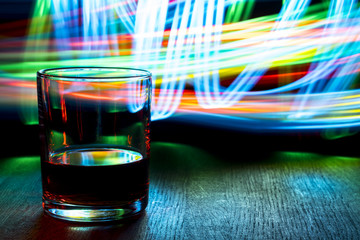 A glass of cognac on the table. The effect of bokeh.