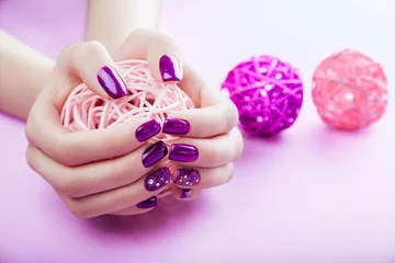 Fotobehang Nagelstudio Vrouw met paarse manicure houdt een bal vast