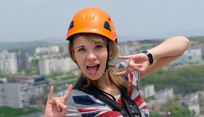 Pretty young smiling girl in the orange helmet showing the tongue