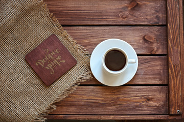 Fototapeta Чашка кофе с салфеткой из мешковины и подставкой под горячие напитки на деревянном коричневом фоне obraz