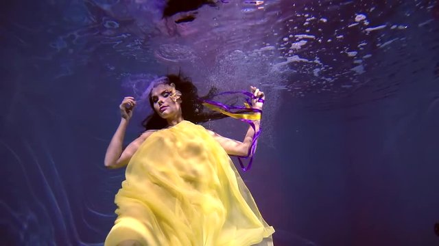 500 frames per second. A wonderful girl in long yellow dress floating under water like in a fairy tale