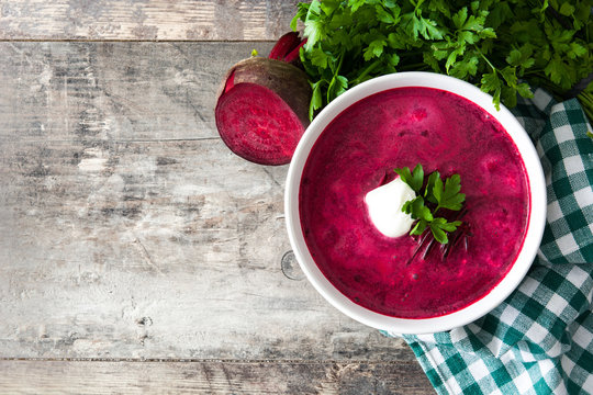 Beet soup in white bowl on wooden table