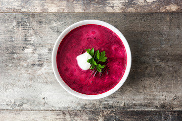 Beet soup in white bowl on wooden table