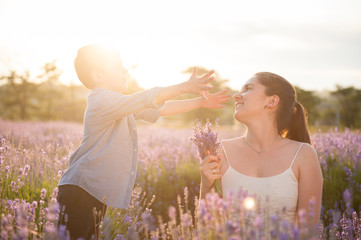 Obraz premium happy cute little boy wants to hug mother and reaches out to her with open arms among flower fields in summer