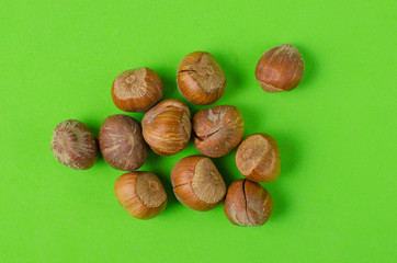 Hazelnut nuts on green background.