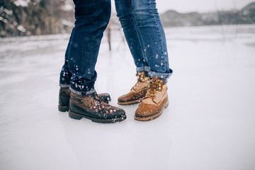 Male and female legs in boots and jeans in the ice background.