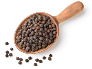 dried black peppercorns in the wooden spoon, isolated on white, top view