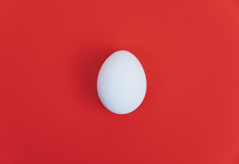 One white egg on red background.