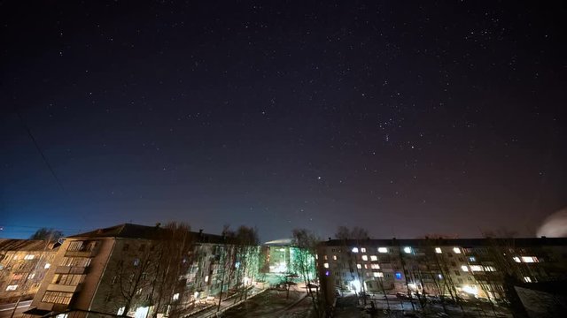 Starry sky moves over a town buildings. Time lapse.