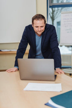 Man standing over laptop in office