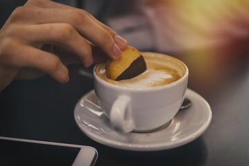 hand with biscuit in the cup of coffee, breakfast and snack