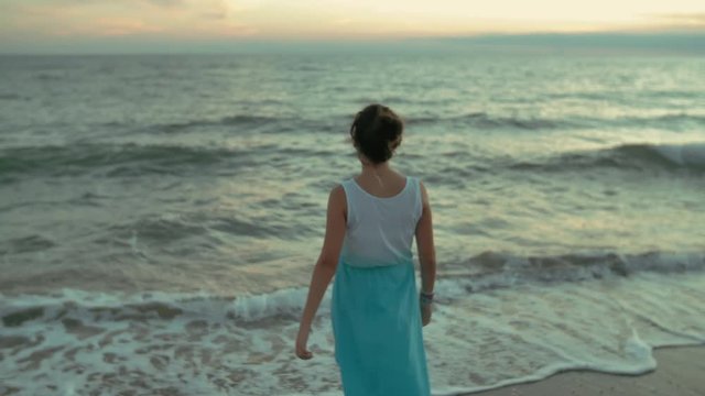 sad girl walking on the beach. shot in slow motion