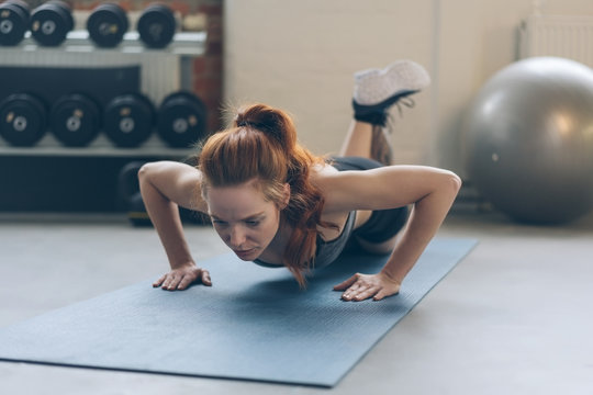 Fit young woman working out doing press ups
