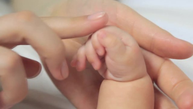 Mother hands caress Newborn baby fingers. Closeup. Beautiful video of maternity