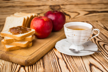 Breakfast toasts with jam on plate and cup of tea on wooden background