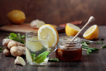 Ginger tea with honey , lemon and mint on old wooden table .