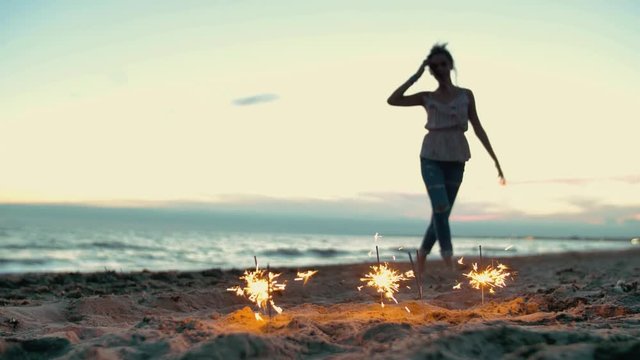 teenager girl with sparklers dancing on the beach. shot in slow motion