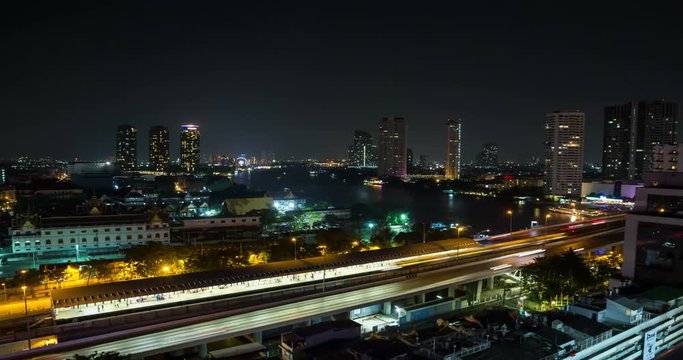 Cityscape time lapse of Bangkok at night featuring skytrain station and river transportation.