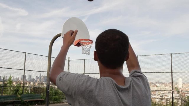 teen shooting basket in park during day - young man playing basketball - scoring - 4K and 1080 HD