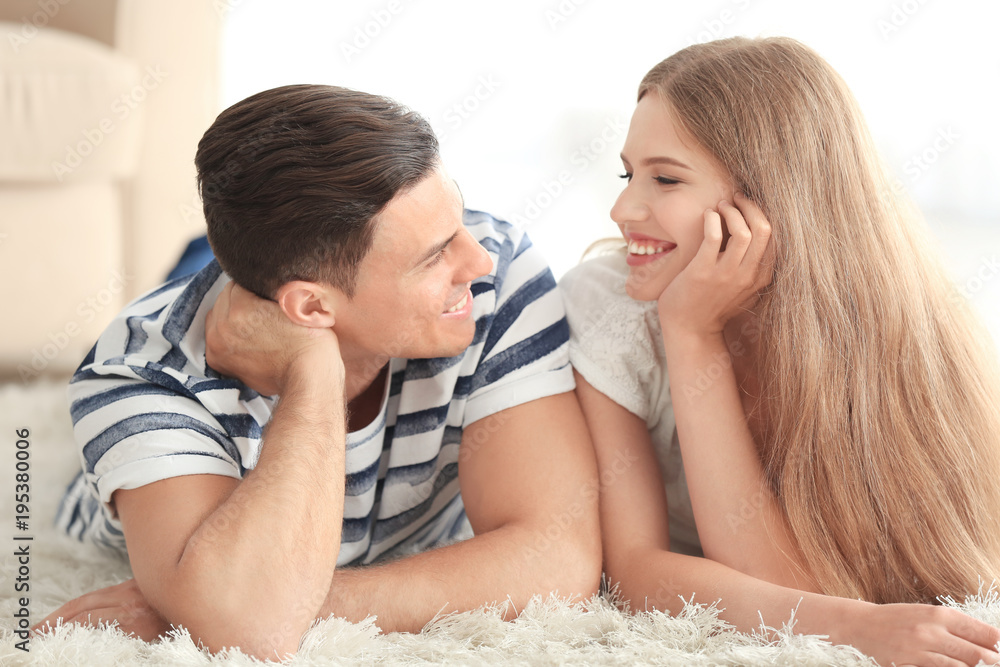 Poster young couple lying on carpet at home