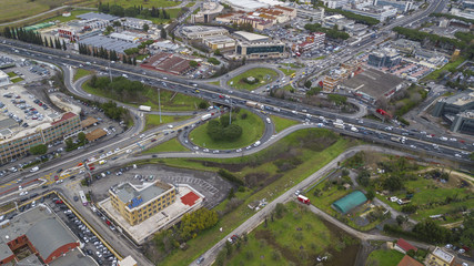 Fototapeta na wymiar Aerial view of a series of highway ramps for immission or exit from the highway at high speed. So many cars, motorcycles, trucks are running on this road near a big city and an industrial area.