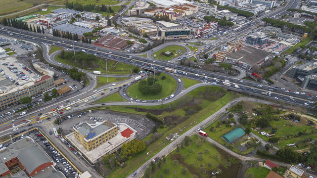 Aerial view of a series of highway ramps for immission or exit from the highway at high speed. So many cars, motorcycles, trucks are running on this road near a big city and an industrial area.