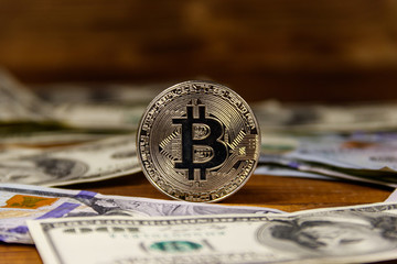 Silver bitcoin and dollars on wooden background