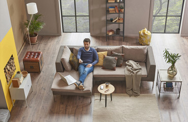 modern living room grey and brown details with man who is watching tv.