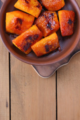 Pumpkin, baked in the oven pumpkin on a wooden background, cooked vegetables in a clay dish in retro style, natural background, vegetarian dish, Mexican cuisine, minimalism, copy space