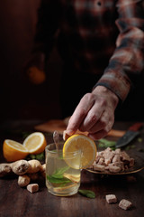 Ginger tea with brown sugar , lemon and mint on old wooden table .