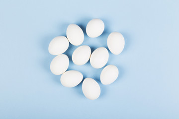 Fototapeta na wymiar White eggs on blue background. Top view