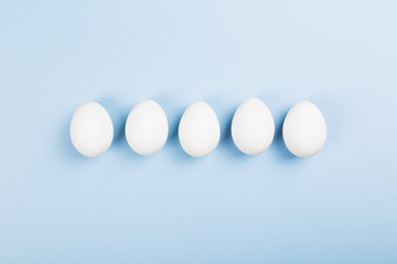 White eggs on blue background. Top view
