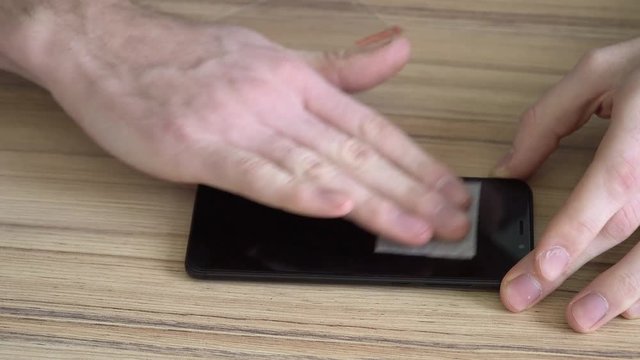 Close-up. Preparing the screen for a new mobile phone. Cleaning with a damp cloth. New protective, chopped, shockproof glass.