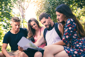 Young people tourists searching for direction using paper map