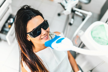 Teeth whitening in dental clinic for pretty female patient