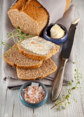 fresh wholegrain bread on white wooden kitchen table with salt and butter can be used as background