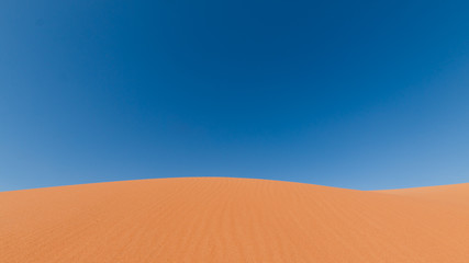 Yellow sand dunes and blue sky in the desert. Negev in Israel. The dunes look like giant waves crossing the sky. 