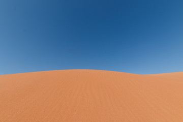 Yellow sand dunes and blue sky in the desert. Negev in Israel. The dunes look like giant waves crossing the sky. 