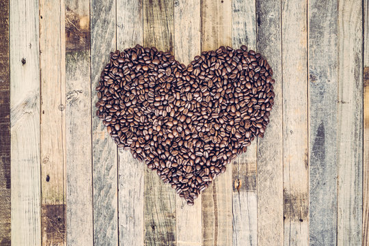 Coffee beans in a shape of heart on wooden background