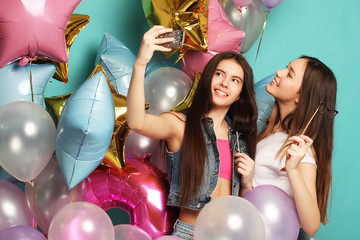Two   girls friends with colorfoul  balloons make selfie on a ph
