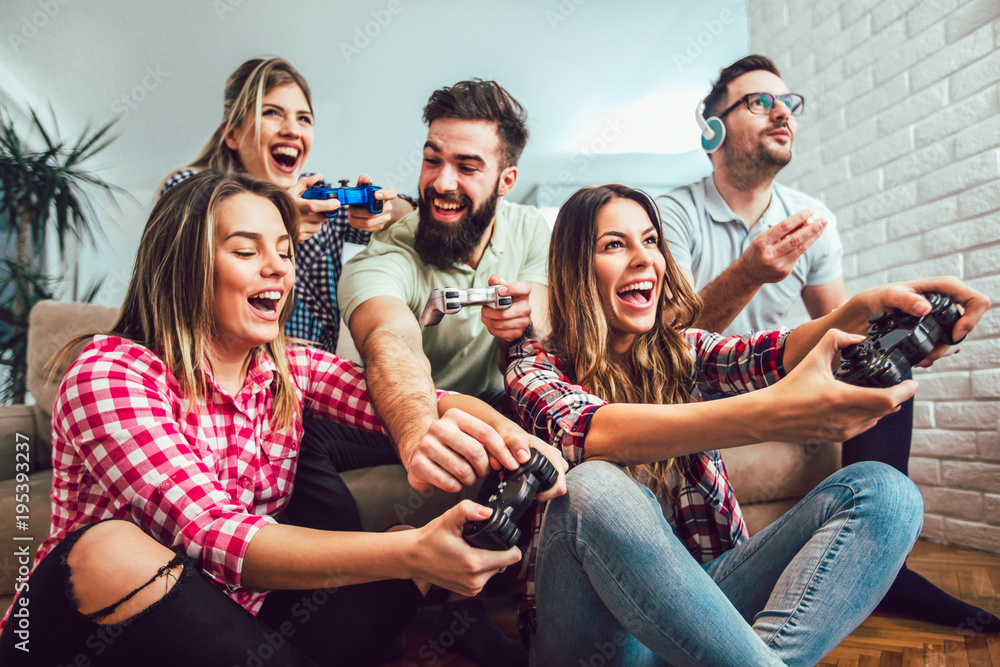 Wall mural group of friends play video games together at home, having fun.