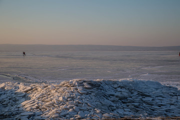 Gefrorener Neusiedler See mit Eisschollen und Eisläufern