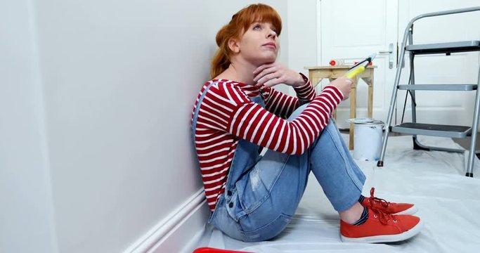 Beautiful woman relaxing after painting wall 