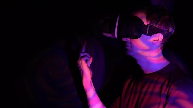 Angry young man in virtual reality headset making obscene hand gesture by showing middle finger