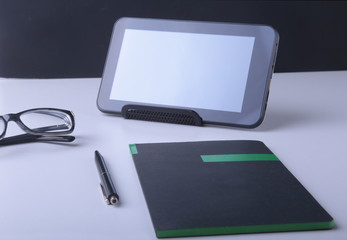 Modern white office desk table with laptop, smartphone and other supplies. Blank notebook page for input the text in the middle. Top view.
